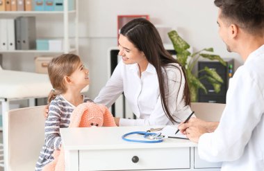Küçük kızı olan bir kadın çocuk doktorunu klinikte ziyaret ediyor.