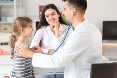 Küçük kızı olan bir kadın çocuk doktorunu klinikte ziyaret ediyor.