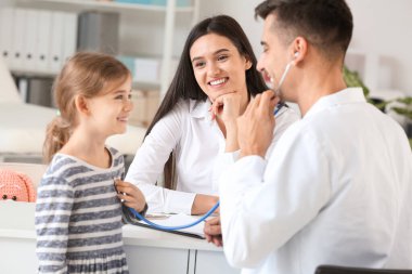 Küçük kızı olan bir kadın çocuk doktorunu klinikte ziyaret ediyor.