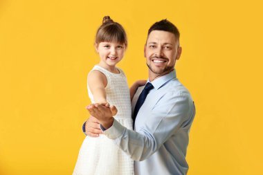 Babası ve küçük kızı renkli arka planda dans ediyorlar.