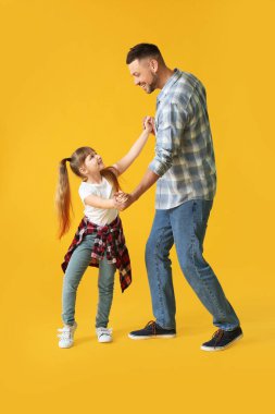 Babası ve küçük kızı renkli arka planda dans ediyorlar.