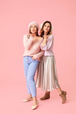 Renkli arka planda kalın kazaklı genç kadınlar