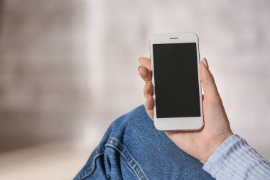 Evde cep telefonu olan genç bir kadın.