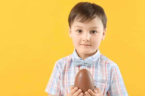 Netter Kleiner Junge Mit Süßem Schokoladenei Auf Farbigem Hintergrund — Stockfoto