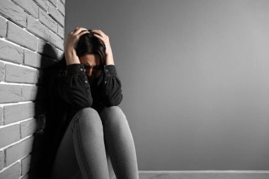 Depresyondaki genç kadın Gri duvarın yanında