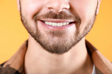 Handsome smiling young man on color background, closeup
