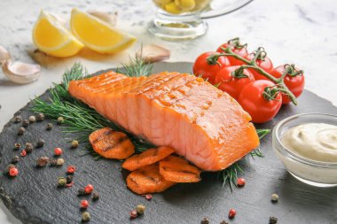 Pişmiş somon filetosu, sebze, sos ve baharat tabakta, yakın plan.