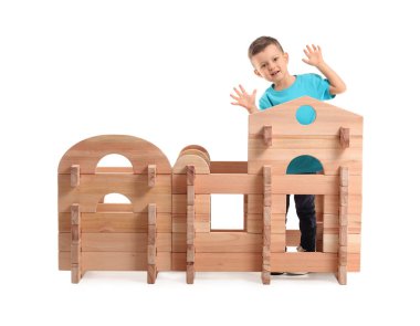 Küçük çocuk beyaz arka planda paravan evle oynuyor.