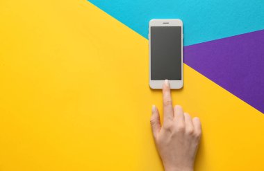 Renkli arka planda cep telefonu olan bir kadın el