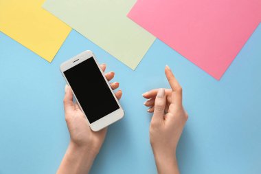 Renkli arka planda cep telefonu olan kadın elleri