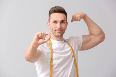 Kilo verme hapı ve arka planda şerit bulunan genç bir adam.