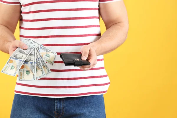 Man with purse and money on color background, closeup