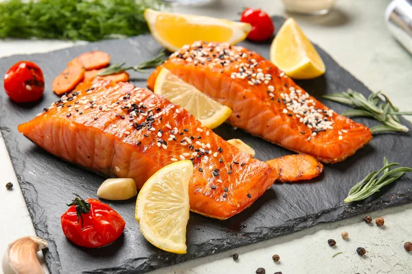 Cooked salmon fillet and vegetables on slate plate