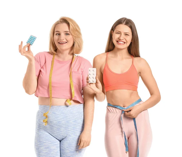 Beyaz arka planda kilo verme hapları olan kadınlar