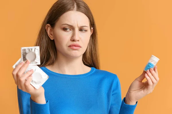 Thoughtful Young Woman Birth Control Pills Condoms Color Background — Stock Photo, Image