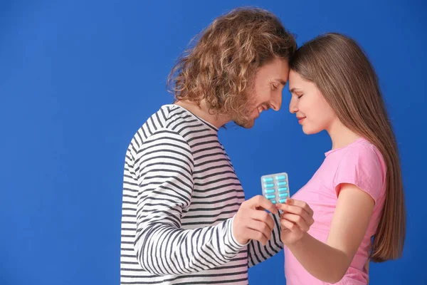Young couple with oral erectile dysfunction medication on color background