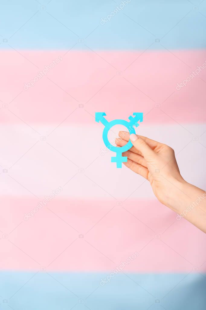 Female hand with symbol of transgender on color background