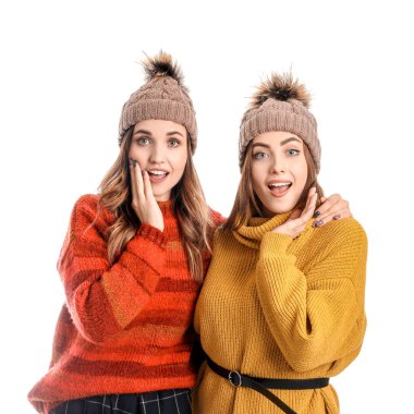 Beyaz arka planda sıcak süveter giyen şaşırmış genç kadınlar.