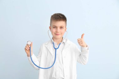 Sevimli küçük doktor, arka planda baş parmak hareketi gösteriyor.