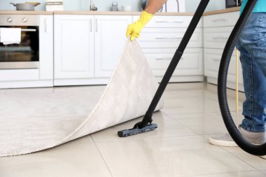 Genç adam mutfakta yerleri süpürüyor.