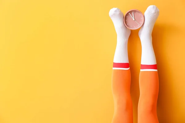 Çoraplı Genç Kadın Bacakları Renk Arka Planında Çalar Saat — Stok fotoğraf