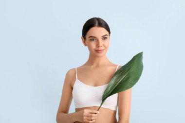 Renkli arka planda tropikal yaprağı olan güzel genç bir kadın.