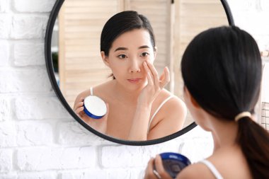 Güzel genç Asyalı kadın evde krem sürüyor.