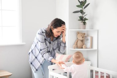 Doğum sonrası depresyondan muzdarip genç bir kadın yatağın yanında bebeğiyle birlikte.