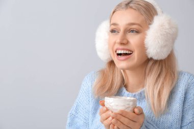 Gri arka planda bir fincan çayı olan güzel genç bir kadın.