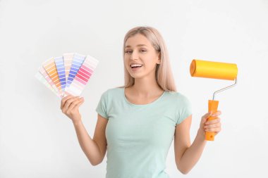 Beyaz arka planda renk örnekleri ve boya silindiri olan genç bir kadın.