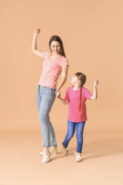 Mutlu anne ve küçük kızı renkli arka planda dans ediyorlar