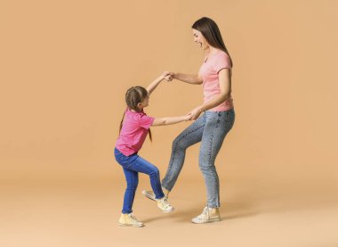 Mutlu anne ve küçük kızı renkli arka planda dans ediyorlar