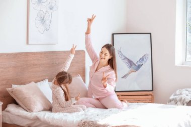 Mutlu bir anne ve kızının yatak odasında dans ettiği bir sabah.