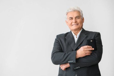 Arka planda çantası olan kıdemli bir işadamı.