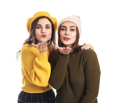 Sıcak kazaklı genç kadınlar beyaz arka planda öpüşüyorlar.