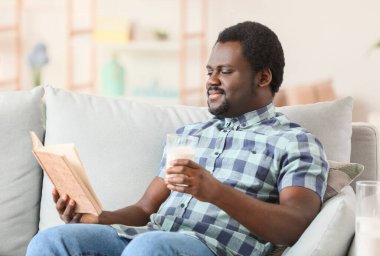 Evde sütlü kitap okuyan genç bir Afro-Amerikalı.