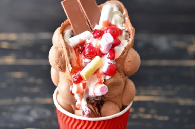 Koyu ahşap arka planda lezzetli balonlu waffle bardağı.