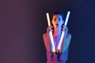 Koyu arkaplanda neon lambaları olan güzel bir kadının tonlu portresi.