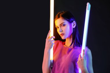 Koyu arkaplanda neon lambaları olan güzel bir kadının tonlu portresi.