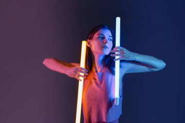 Koyu arkaplanda neon lambaları olan güzel bir kadının tonlu portresi.