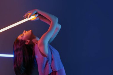 Koyu arkaplanda neon lambaları olan güzel bir kadının tonlu portresi.