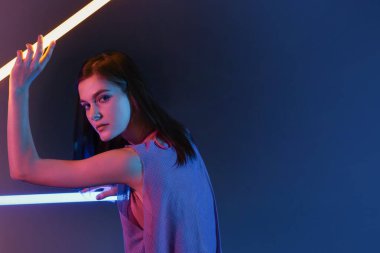 Koyu arkaplanda neon lambaları olan güzel bir kadının tonlu portresi.