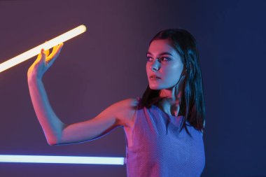 Koyu arkaplanda neon lambaları olan güzel bir kadının tonlu portresi.