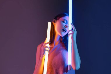 Koyu arkaplanda neon lambaları olan güzel bir kadının tonlu portresi.