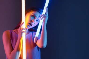 Koyu arkaplanda neon lambaları olan güzel bir kadının tonlu portresi.