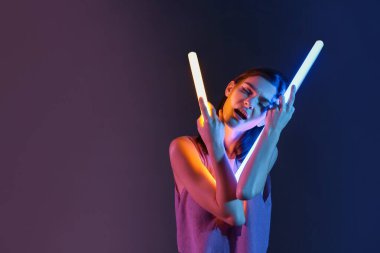 Koyu arkaplanda neon lambaları olan güzel bir kadının tonlu portresi.