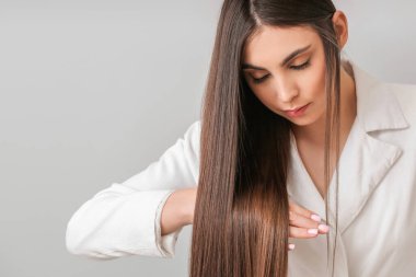 Gri arka planda güzel düz saçları olan genç bir kadın.
