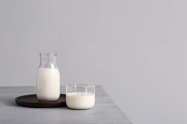 Gri arka planda taze süt bulunan cam eşyalar.