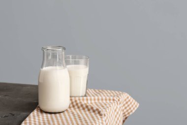 Gri arka planda taze süt bulunan cam eşyalar.