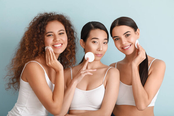 Beautiful young women with cotton pads on color background